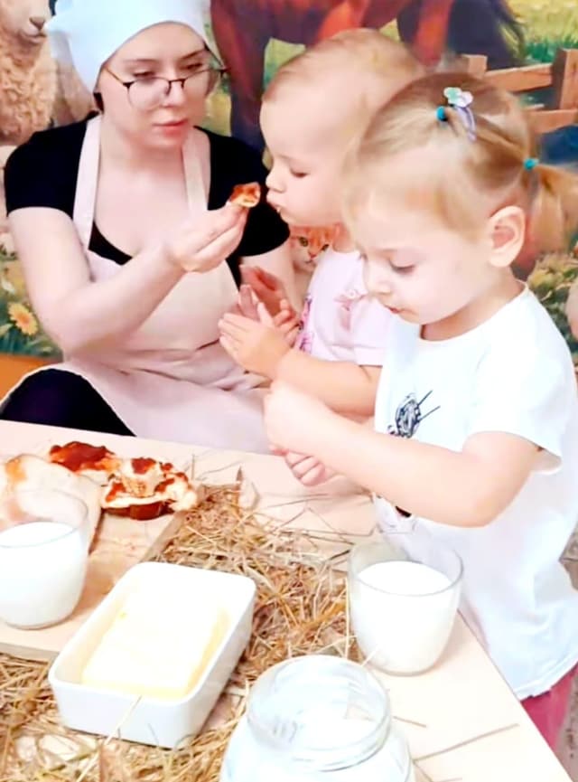 Opiekunka częstuje dziewczynkę chlebem z dżemem